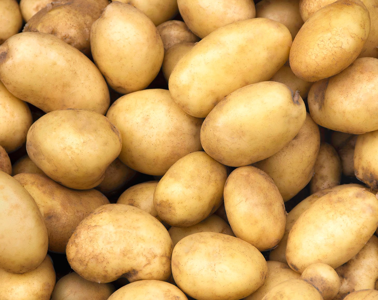 Pile of fresh potatoes on sale in vegetable stand display at sup