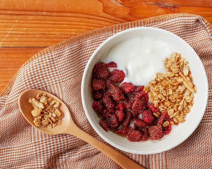 bowl-of-yogurt-with-granola-and-dried-strawberry-on-wood-table