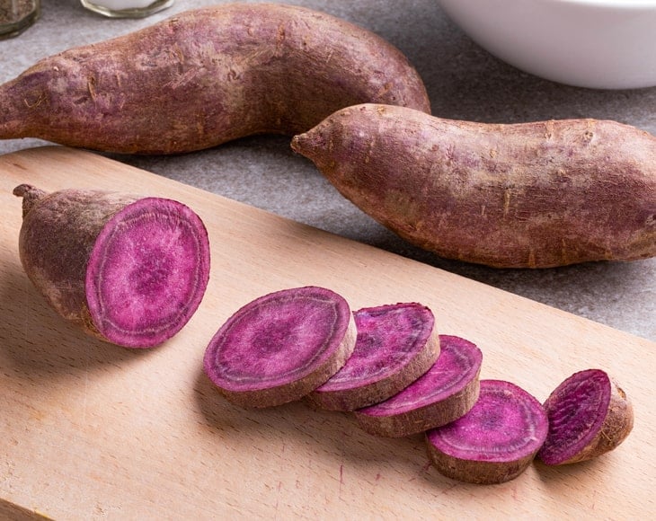 purple-sweet-potatoes-sliced-one-cutting-board-min